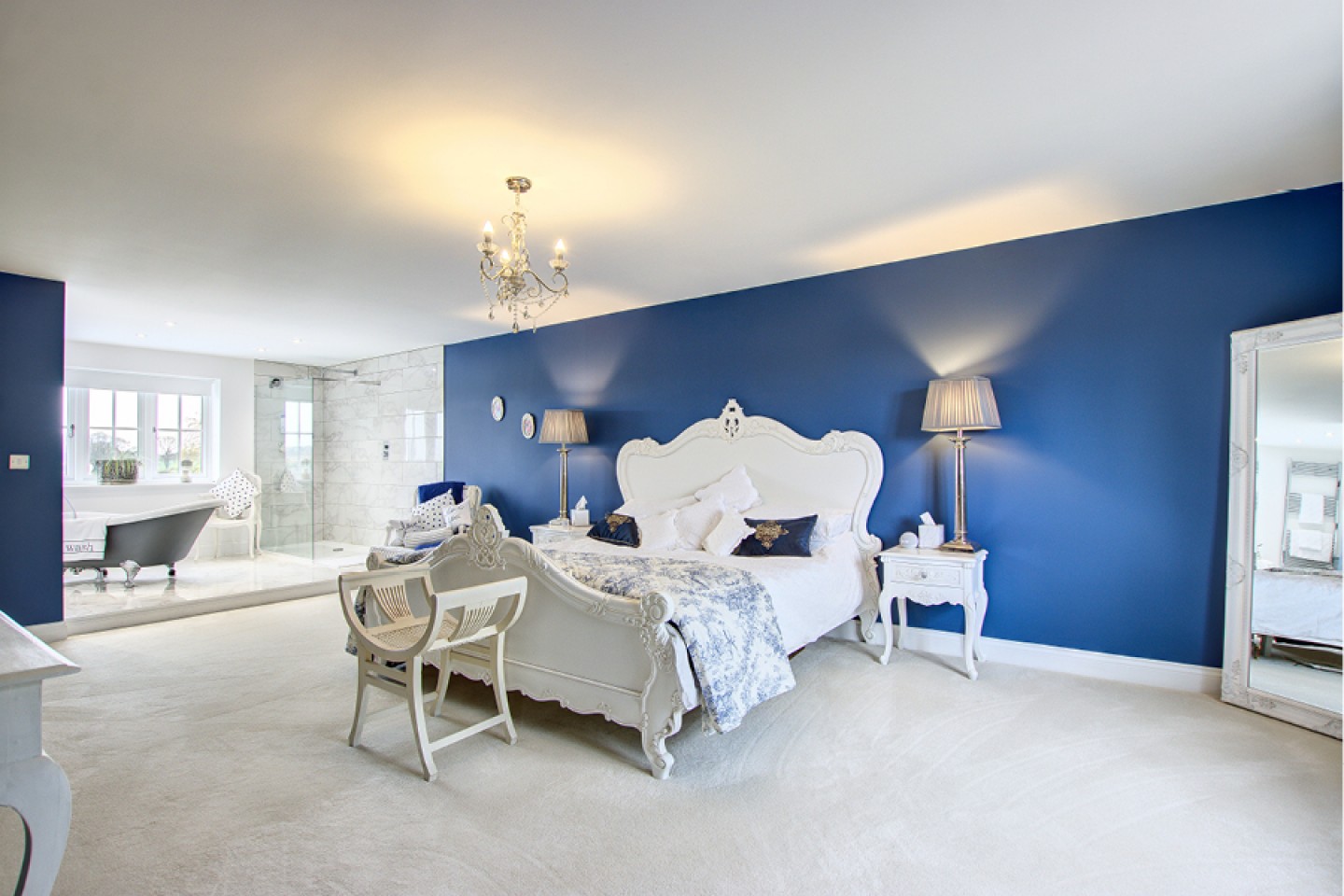 Master bedroom with open bathroom and statement blue walls